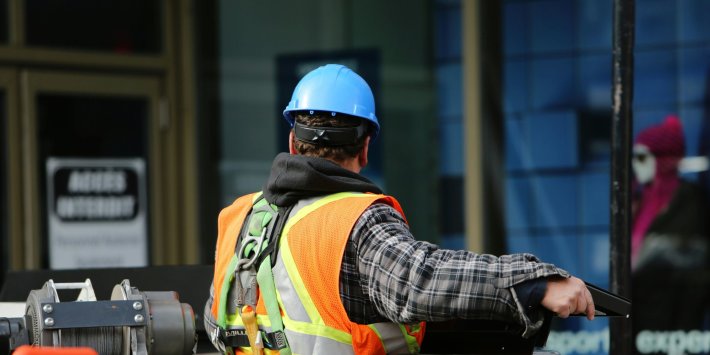 A man facing away in a hard hat working on a construction site