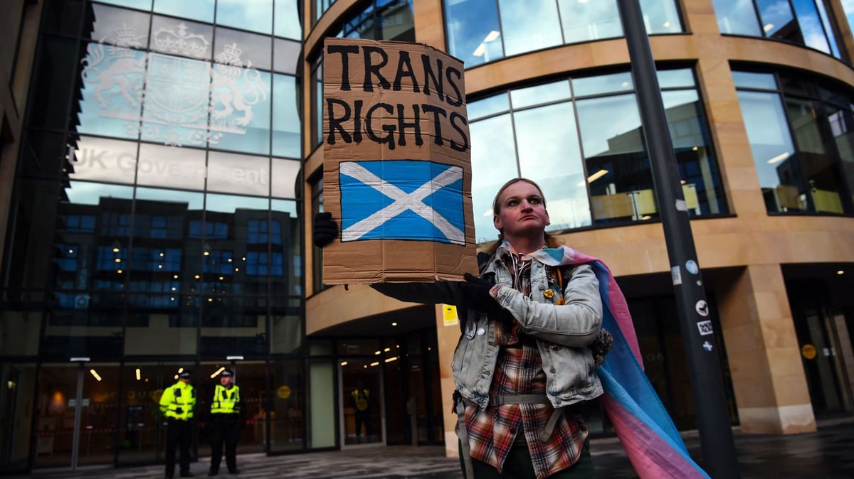 A trans rights protester with a Scottish flag